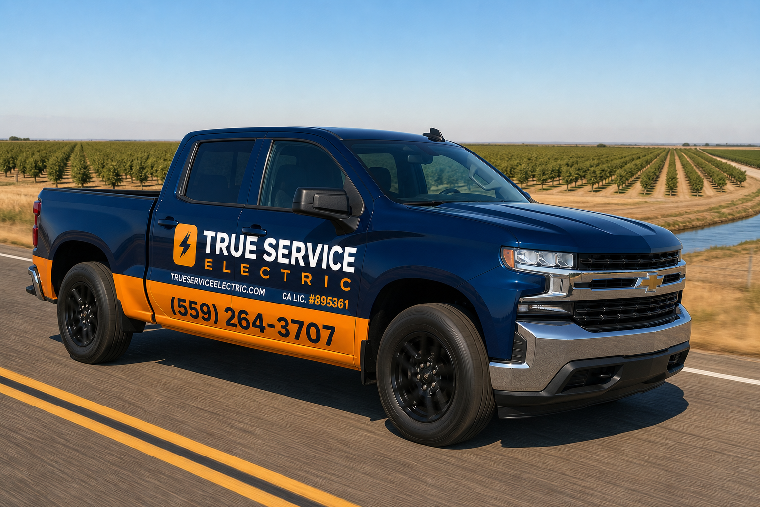 A dark blue and orange pickup truck with True Service Electric lettering driving past orchard rows.